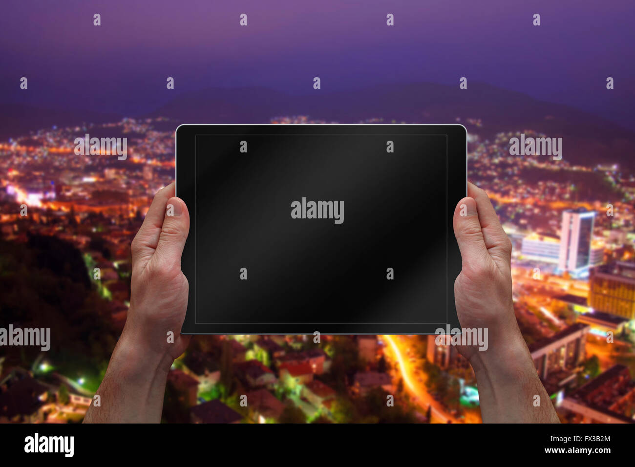Man holding tablette avec écran vide. Nuit paysage ville en arrière-plan. Banque D'Images