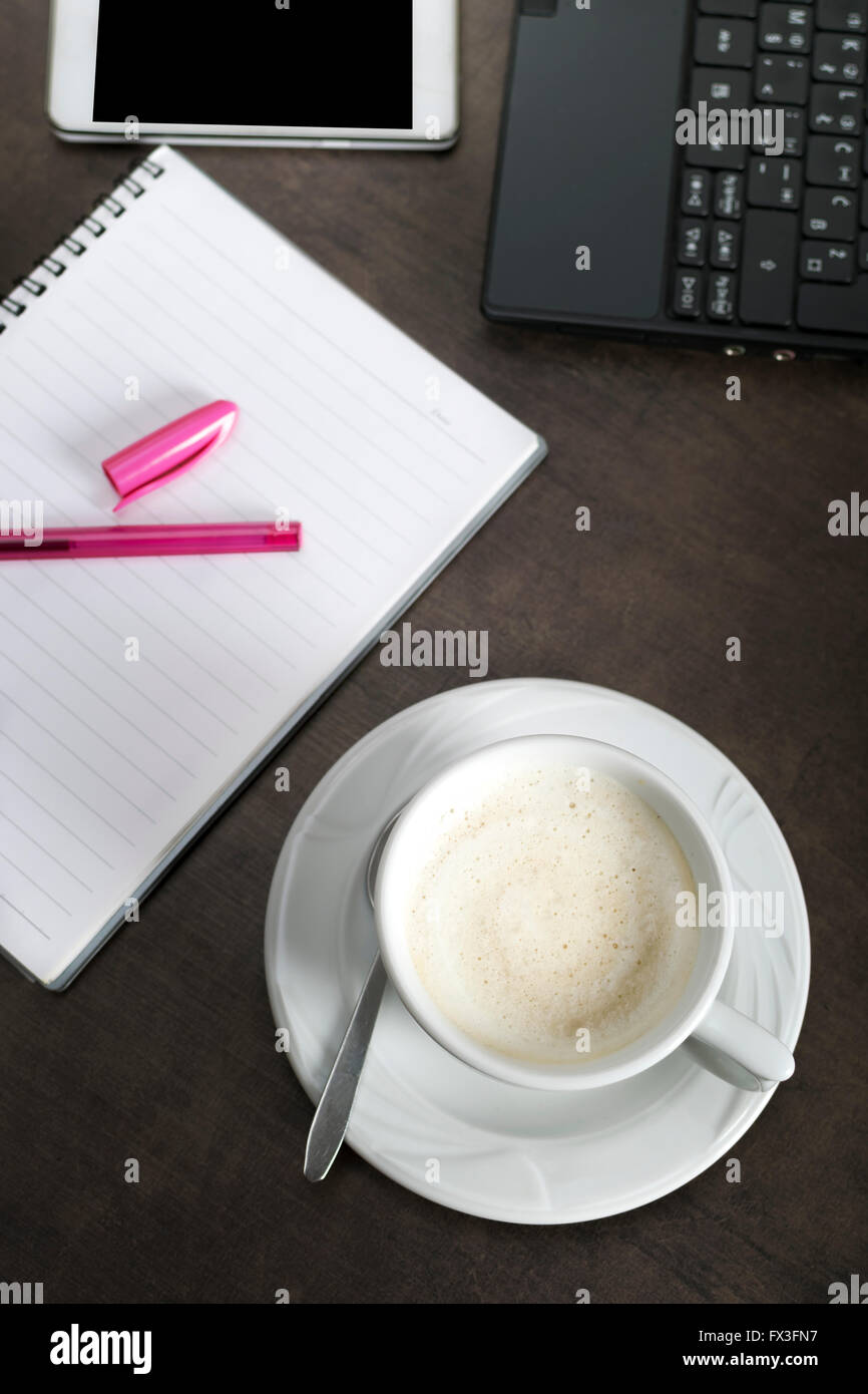 Blank notepad, téléphone, ordinateur portable et tasse à café sur table en bois bureau Banque D'Images