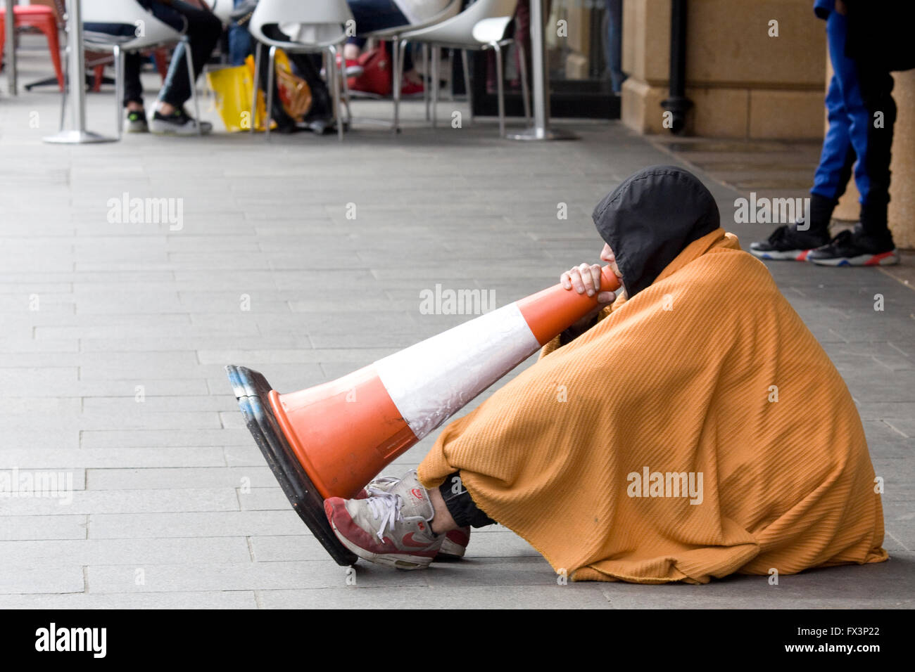 Jeune homme chantant grâce à un cône de circulation de l'argent pour la mendicité dans les rues de Londres Banque D'Images