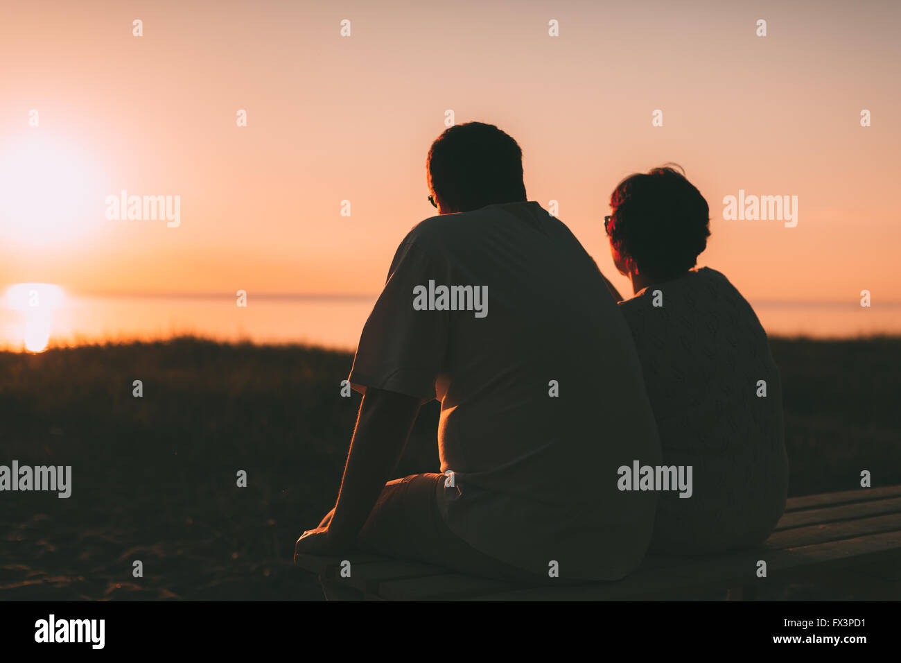 Vue de côté un couple marié une silhouette assise sur un banc. Banque D'Images