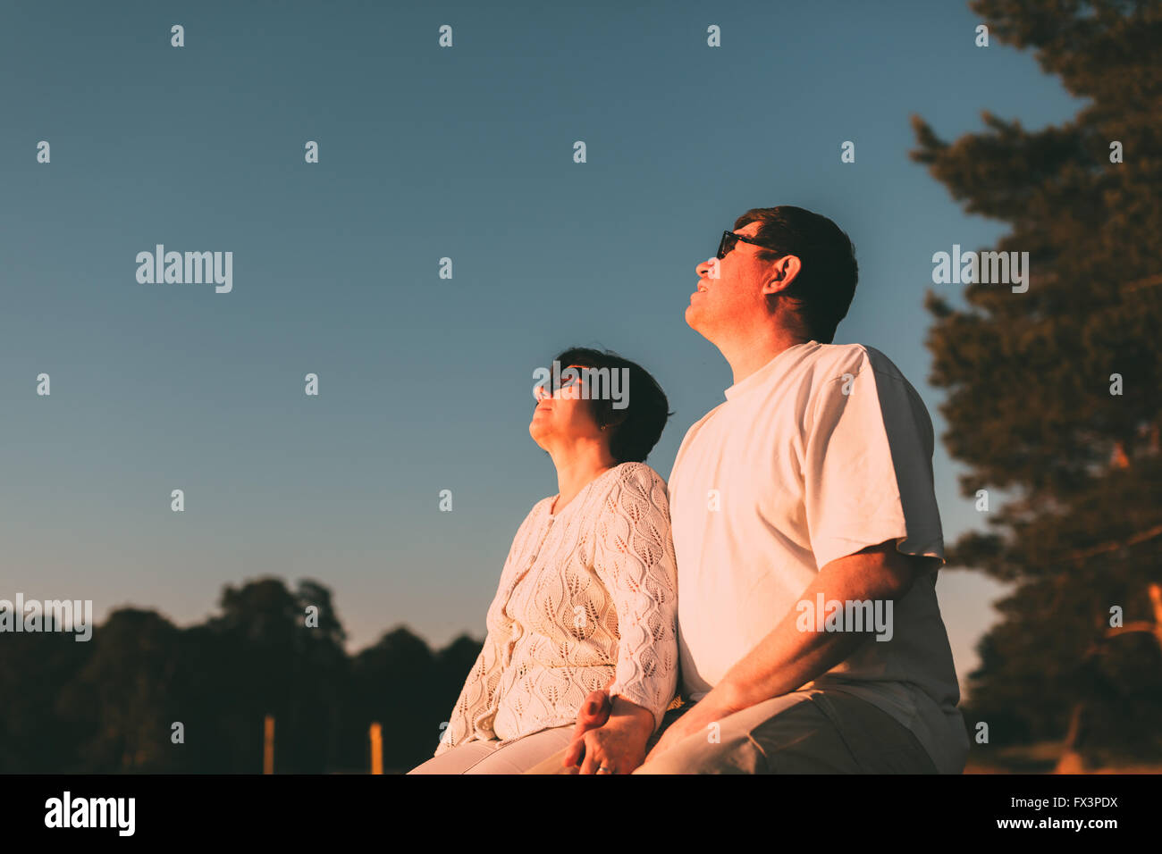 Couple assis sur un banc et de regarder le ciel. Banque D'Images