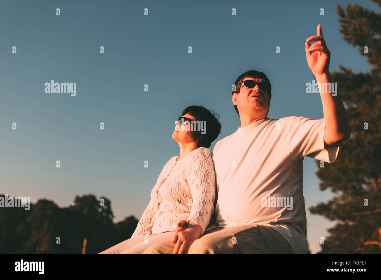 Couple assis sur un banc et de regarder le ciel. Banque D'Images