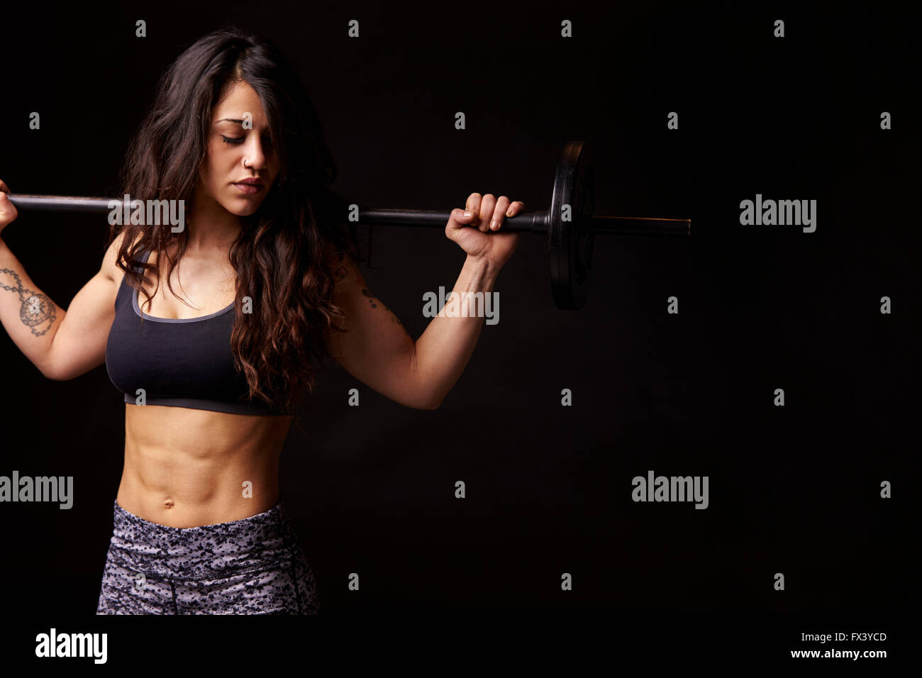 Muscular dark haired woman holding barbell, regardant vers le bas Banque D'Images