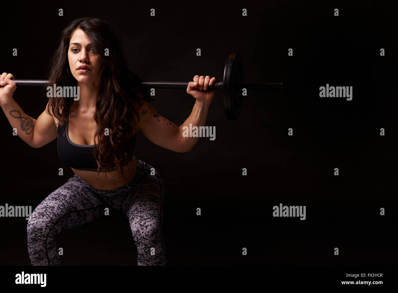 Dark haired woman musculaire en demi-squat avec haltères longs Banque D'Images
