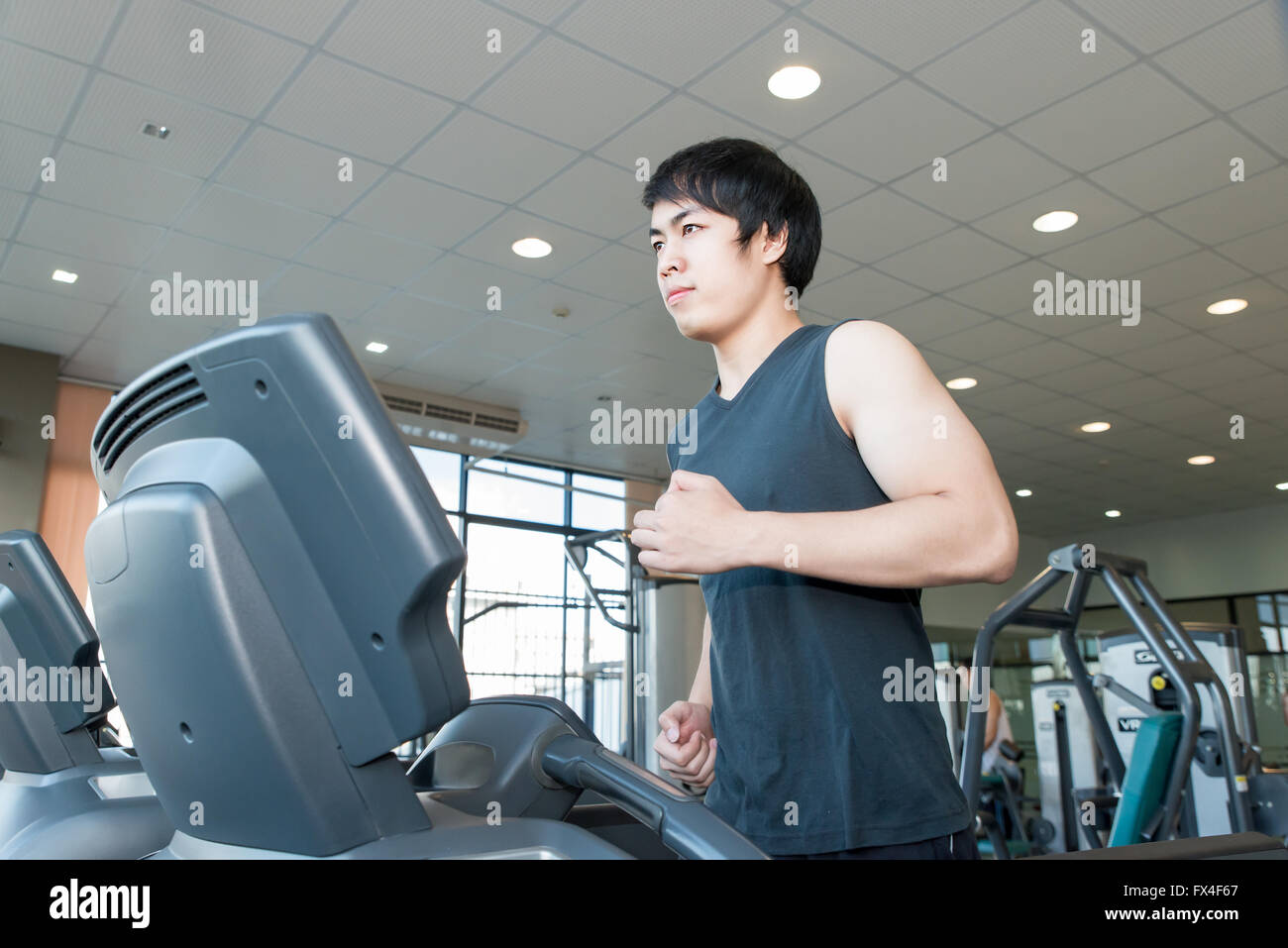 Asian young man running on treadmill in gym Banque D'Images