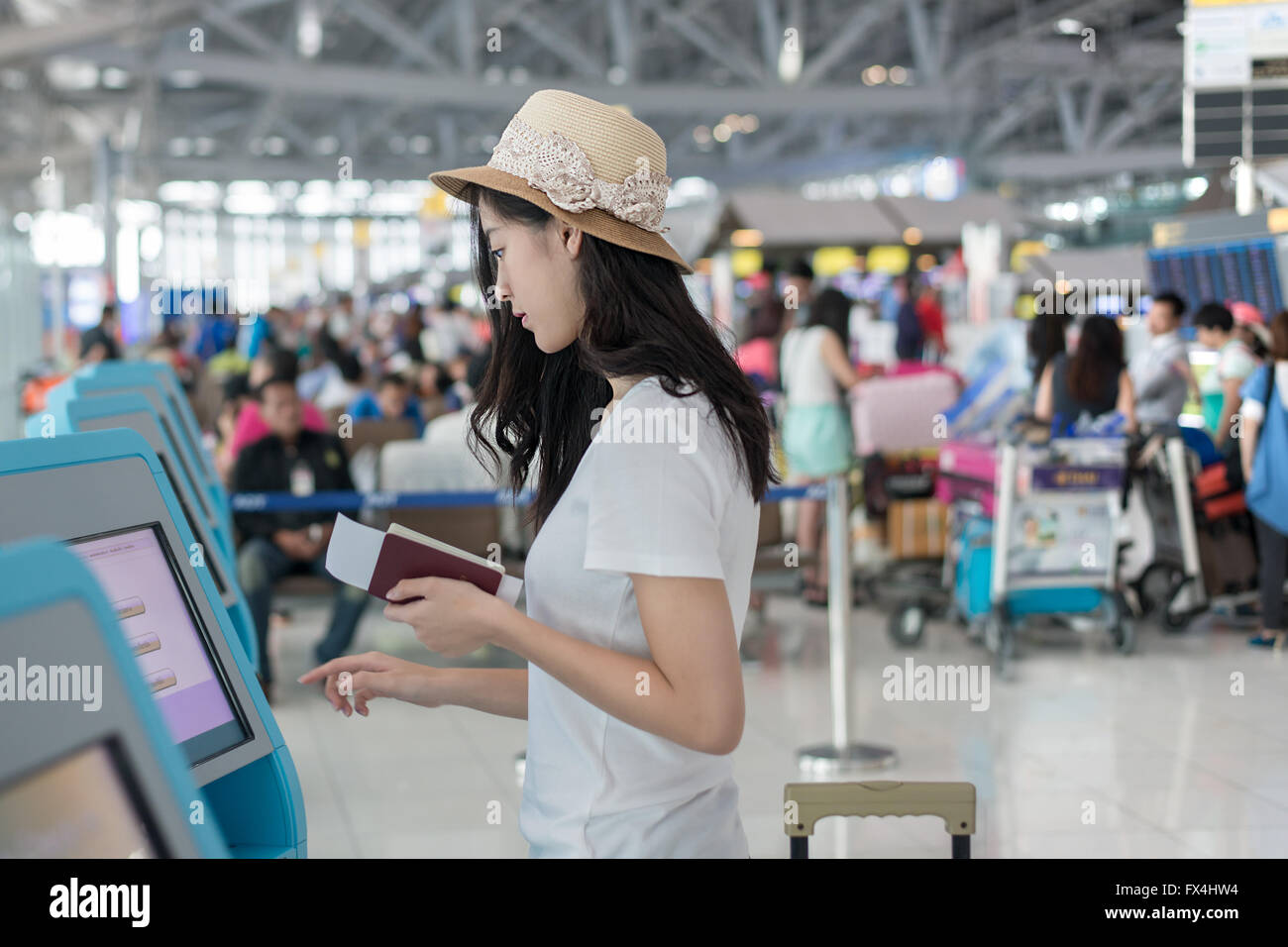 Young Asian woman en utilisant l'enregistrement automatique dans les kiosques à l'aéroport Banque D'Images