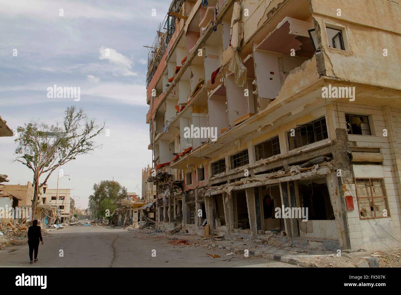 Palmyra, Syrie. Apr 11, 2016. Un civil syrien passe devant un bâtiment endommagé à Palmyra, Syrie centrale, le 11 avril 2016. Des centaines de civils ont été transportées le samedi à la ville antique de Palmyre dans la province centrale de Homs, à la suite de l'armée syrienne d'une récupération de cette ville oasis millénaires, une source gouvernementale a déclaré à Xinhua. Crédit : Yang Zhen/Xinhua/Alamy Live News Banque D'Images