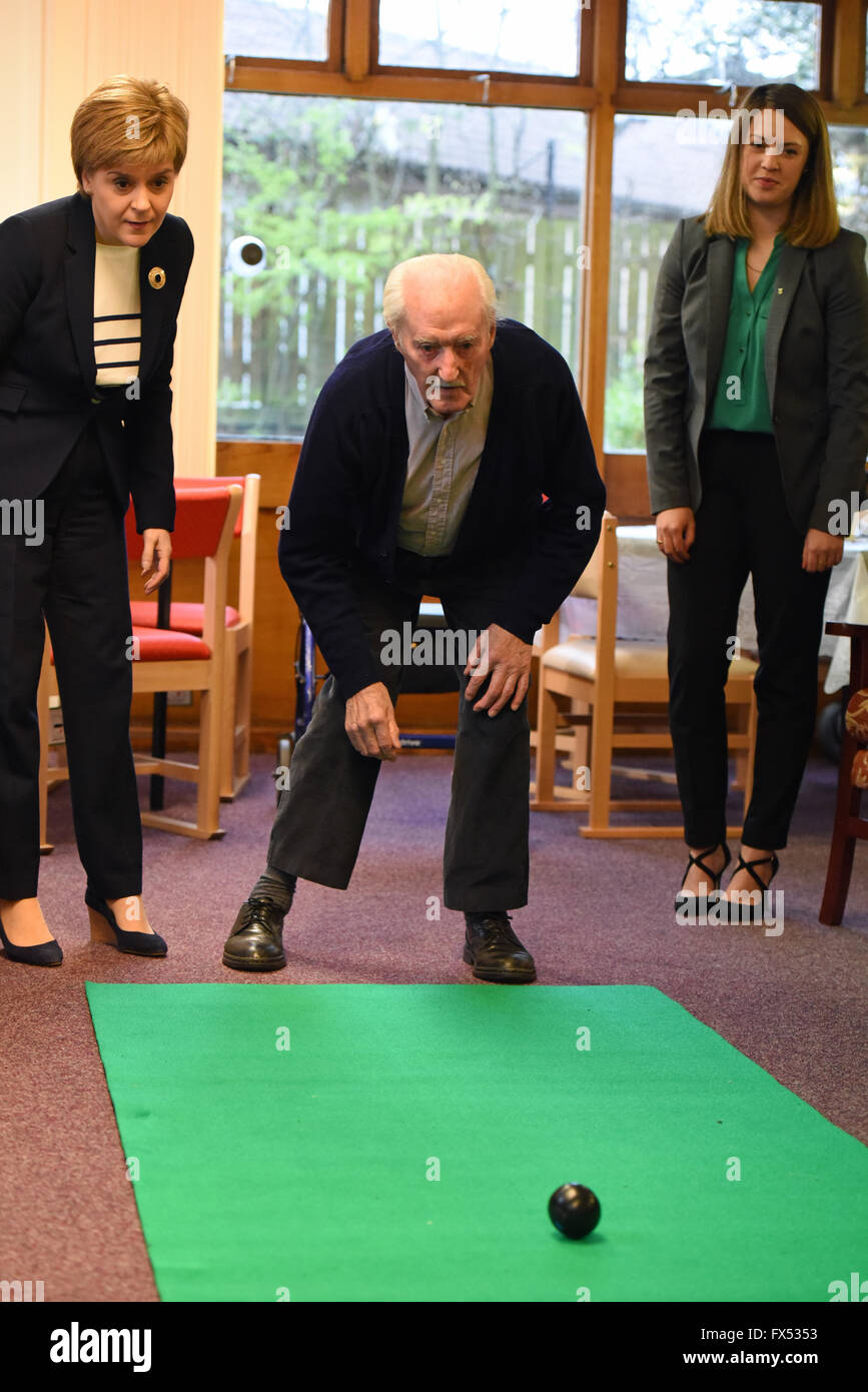 Leven, Ecosse, Royaume-Uni, 12, avril 2016. Premier Ministre de l'Ecosse Nicola Sturgeon (L) et Jenny candidat SNP Gilruth (R) regarder un jeu de pétanque sur tapis une visite à Arden House Projets garderie, pendant la campagne pour les élections du Parlement écossais qui ont lieu le 5 mai, le Crédit : Ken Jack / Alamy Live News Banque D'Images