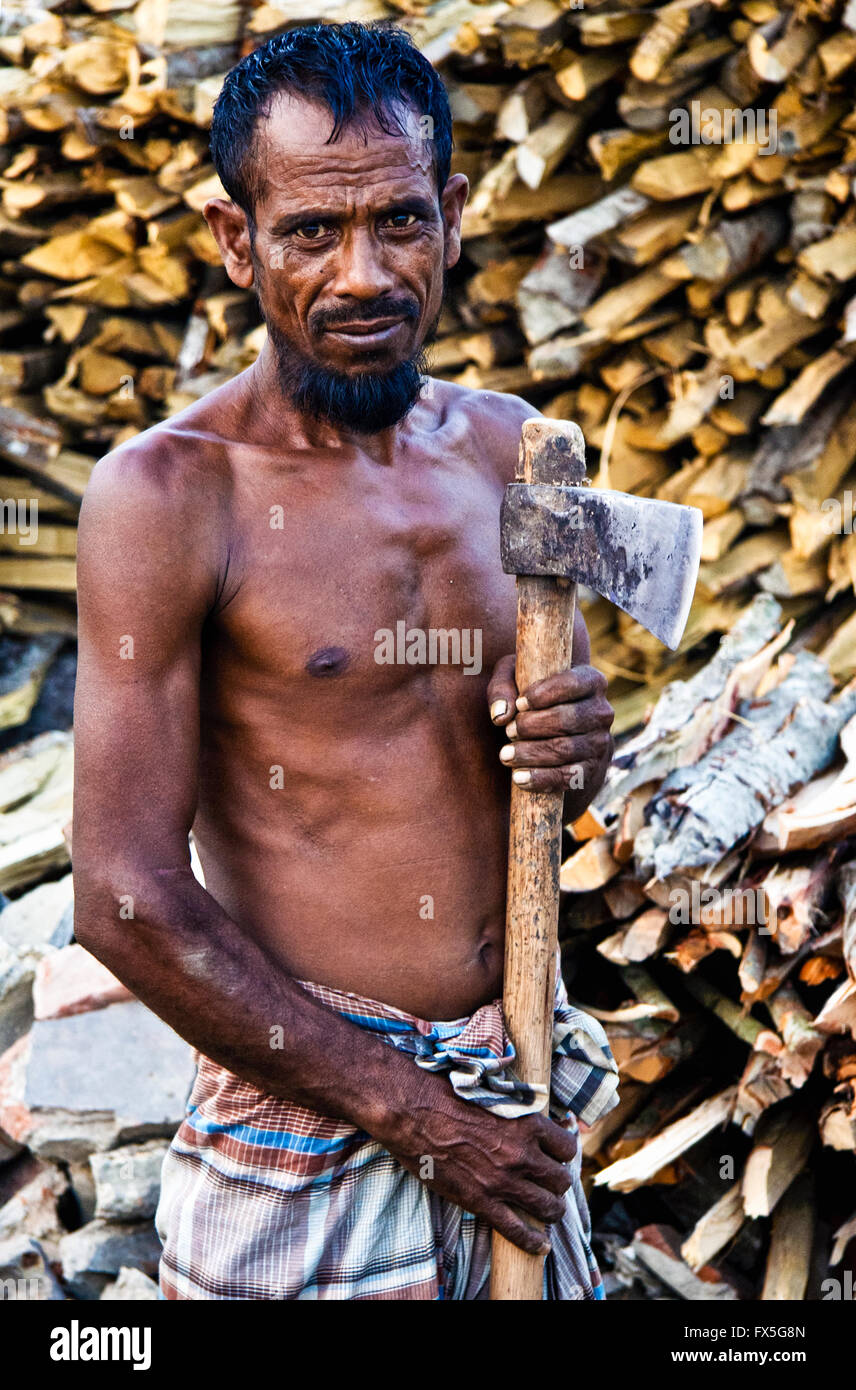Scieur de bois avec une hache et un tas de bois dans la région des Sundarbans, Mongla, Bangladesh Banque D'Images
