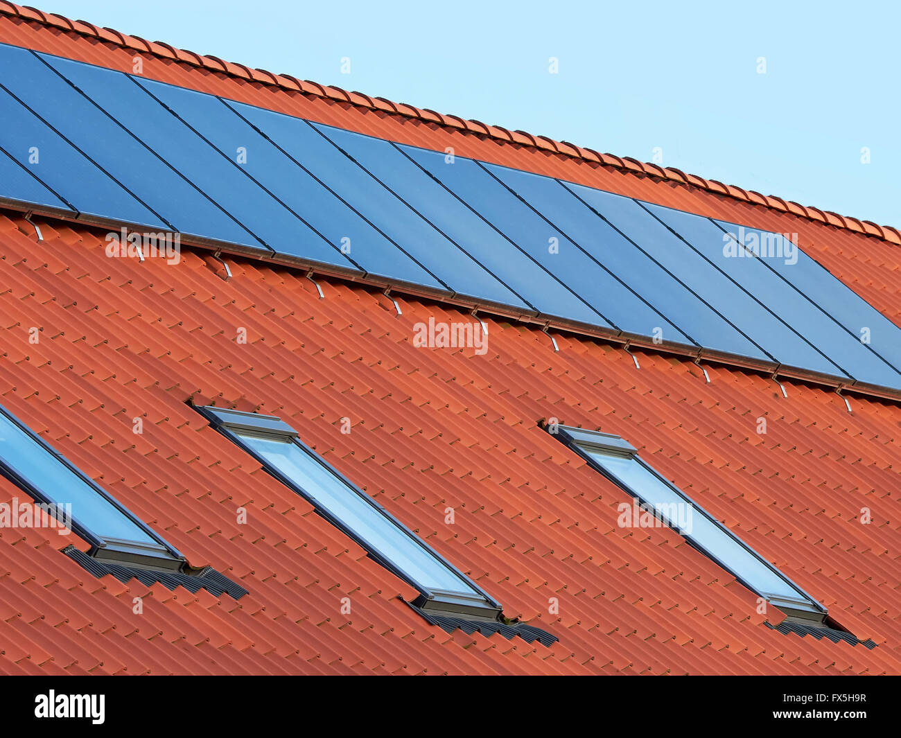 Les capteurs thermiques solaires plaque plane sur un toit en tuiles rouges Banque D'Images