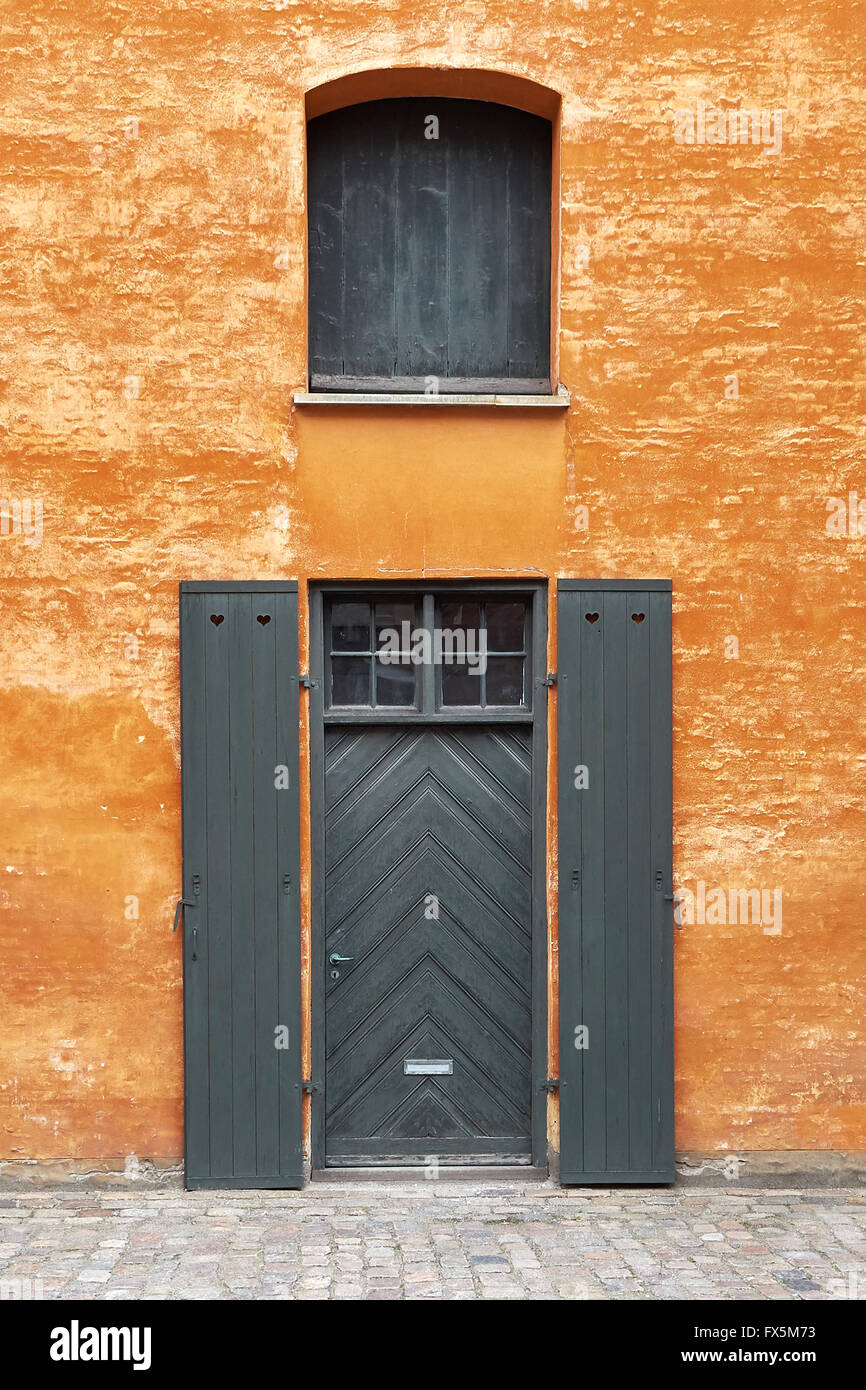 Vieille porte verte sur un mur orange à Copenhague, Danemark Banque D'Images