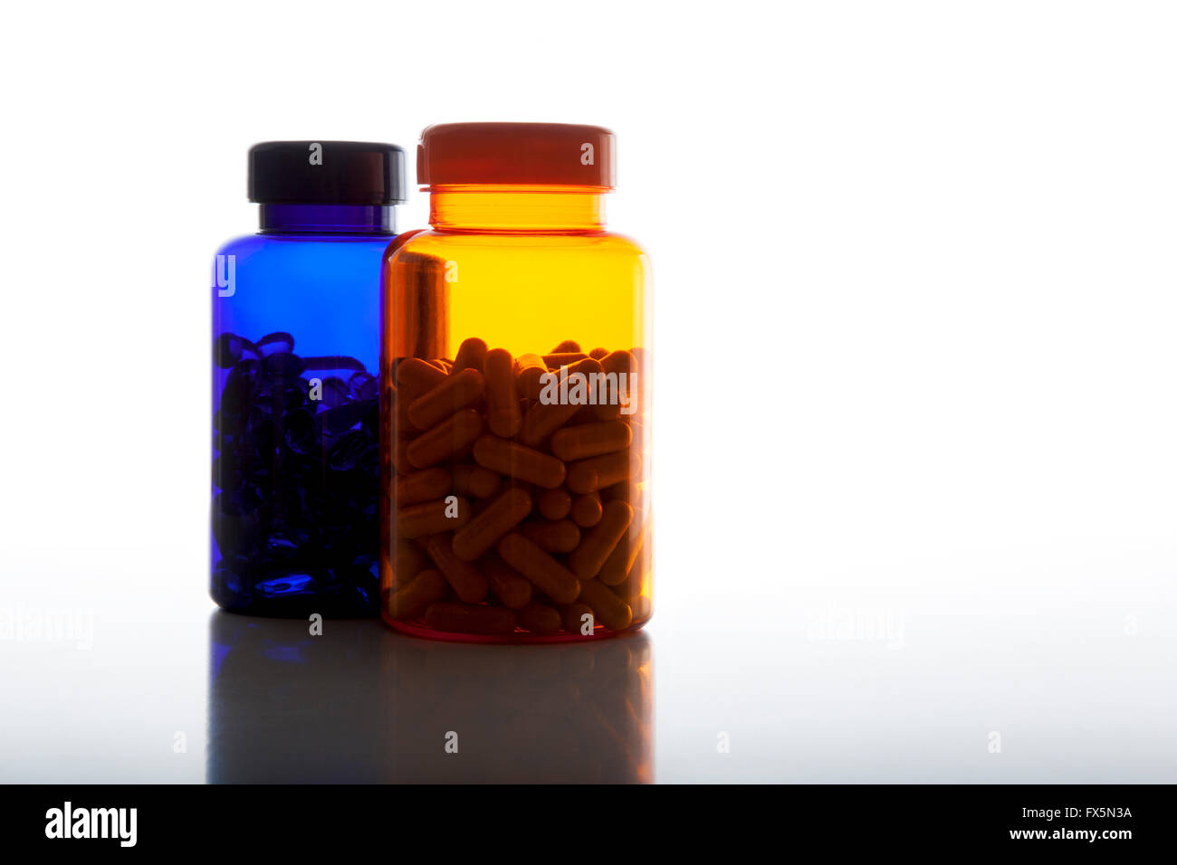 Bouteilles de pilules colorées plein de comprimés contre l'arrière-plan blanc Banque D'Images