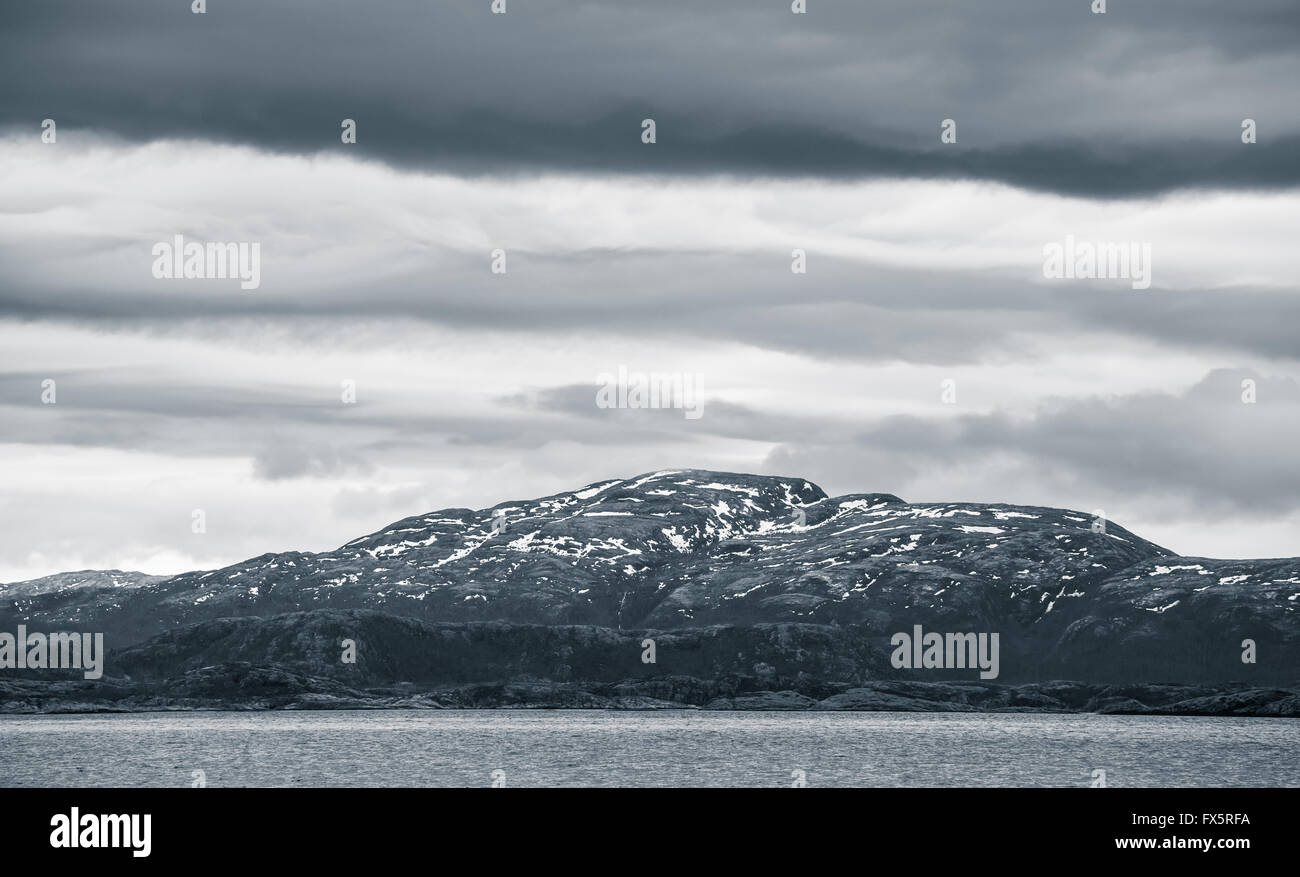 Paysage norvégien sombre avec vue sur la mer côte et les montagnes de neige. Photo monochrome dans les tons bleus, filtre style vintage Banque D'Images