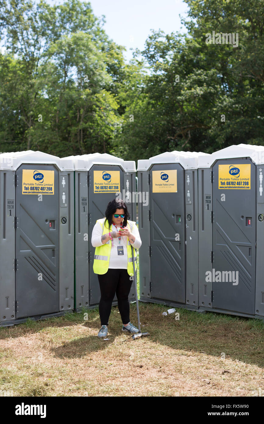 Festival Womad, Wiltshire et de toilettes attendent la regardant mobiel téléphone. Banque D'Images