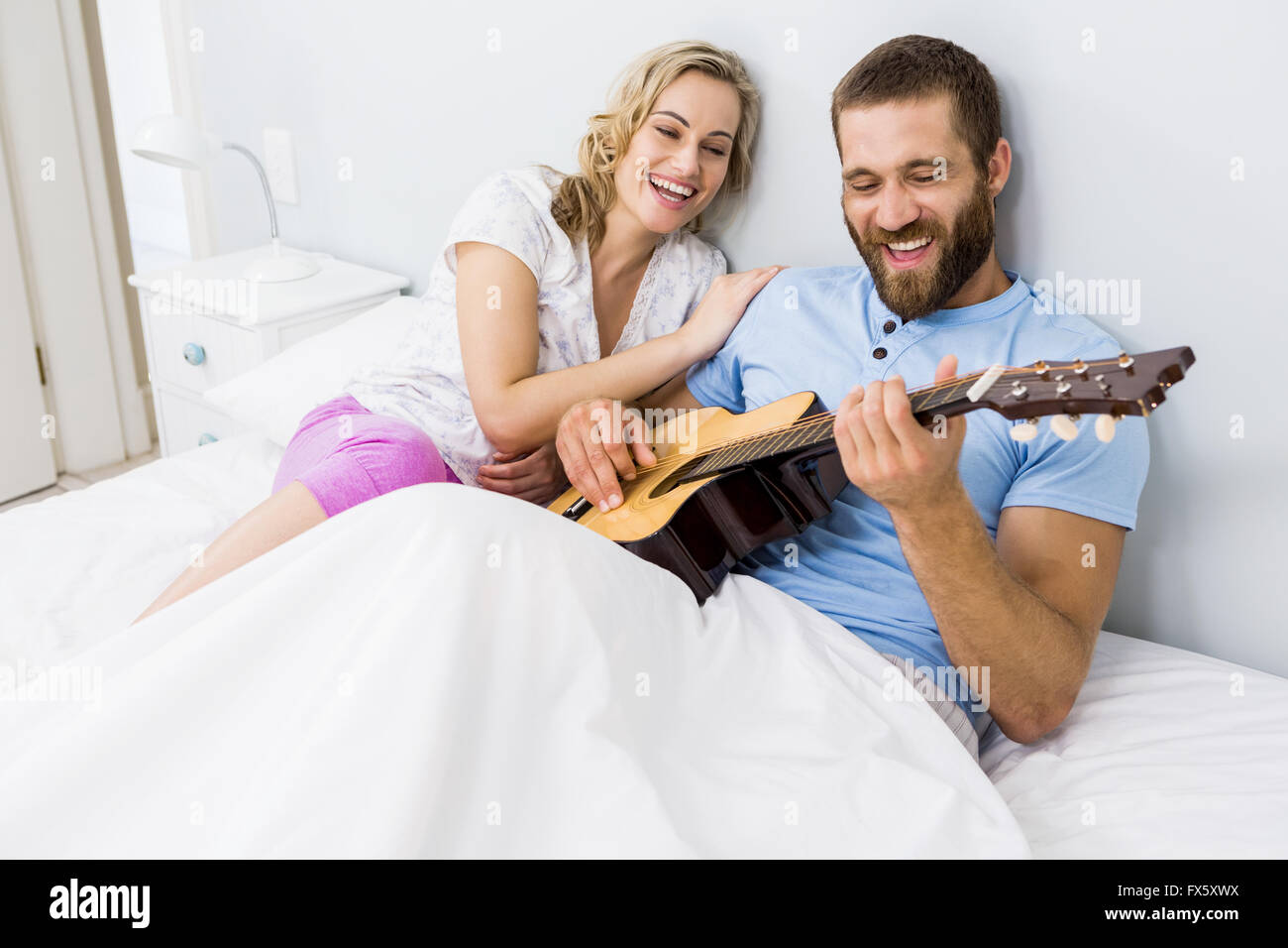 L'homme et de la femme qui joue de la guitare dans le lit Photo Stock -  Alamy
