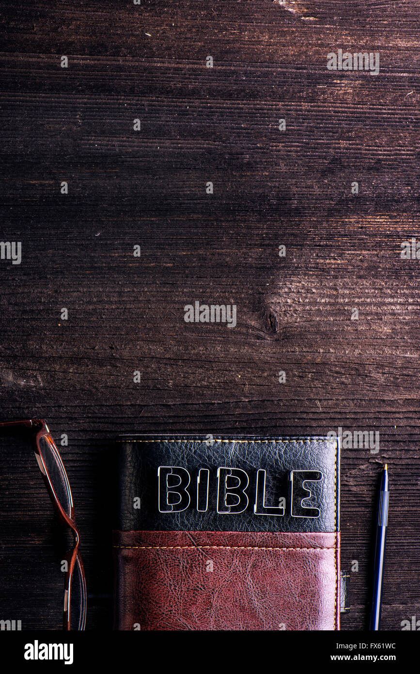 Bible, lunettes et un stylo posé sur une table en bois ancien Banque D'Images