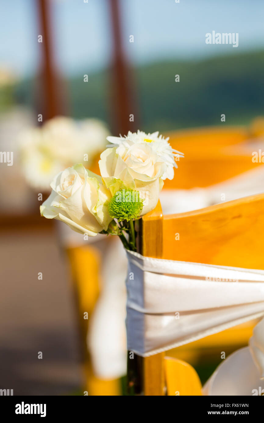 Décor de mariage de fleurs blanches liées à la cérémonie des chaises à ce lieu de plein air. Banque D'Images