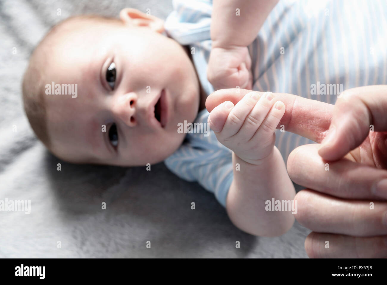 Close up of baby boy jouant avec les doigts de père Banque D'Images