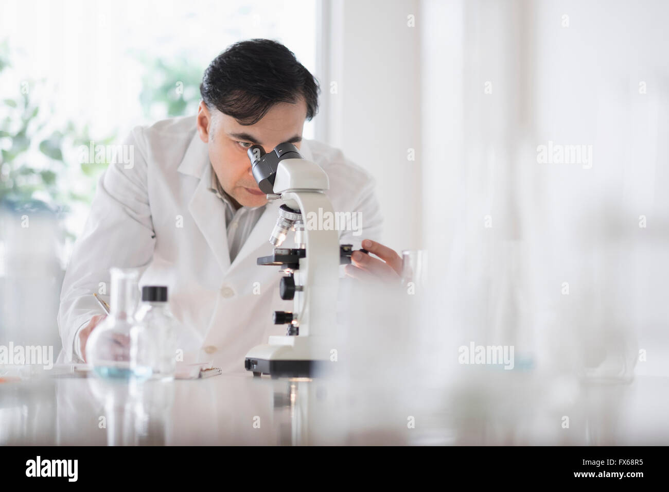 Mixed Race scientist using microscope in laboratory Banque D'Images