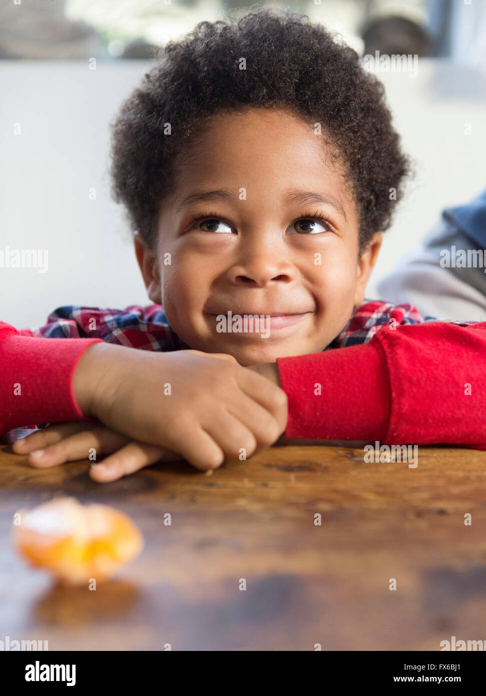 Mixed Race boy smiling at table Banque D'Images