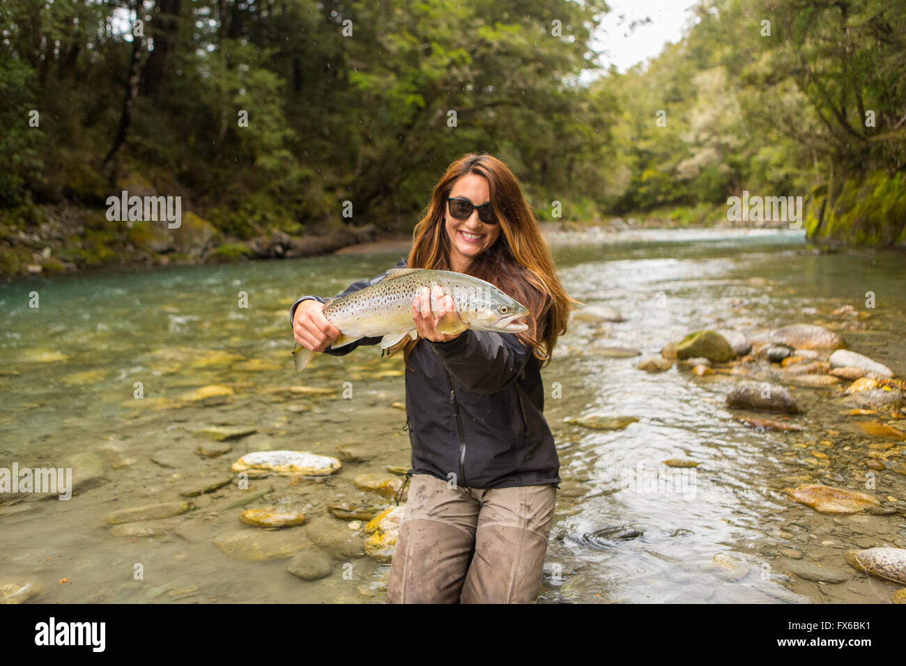 Caucasian woman capture de poissons dans la rivière à distance Banque D'Images