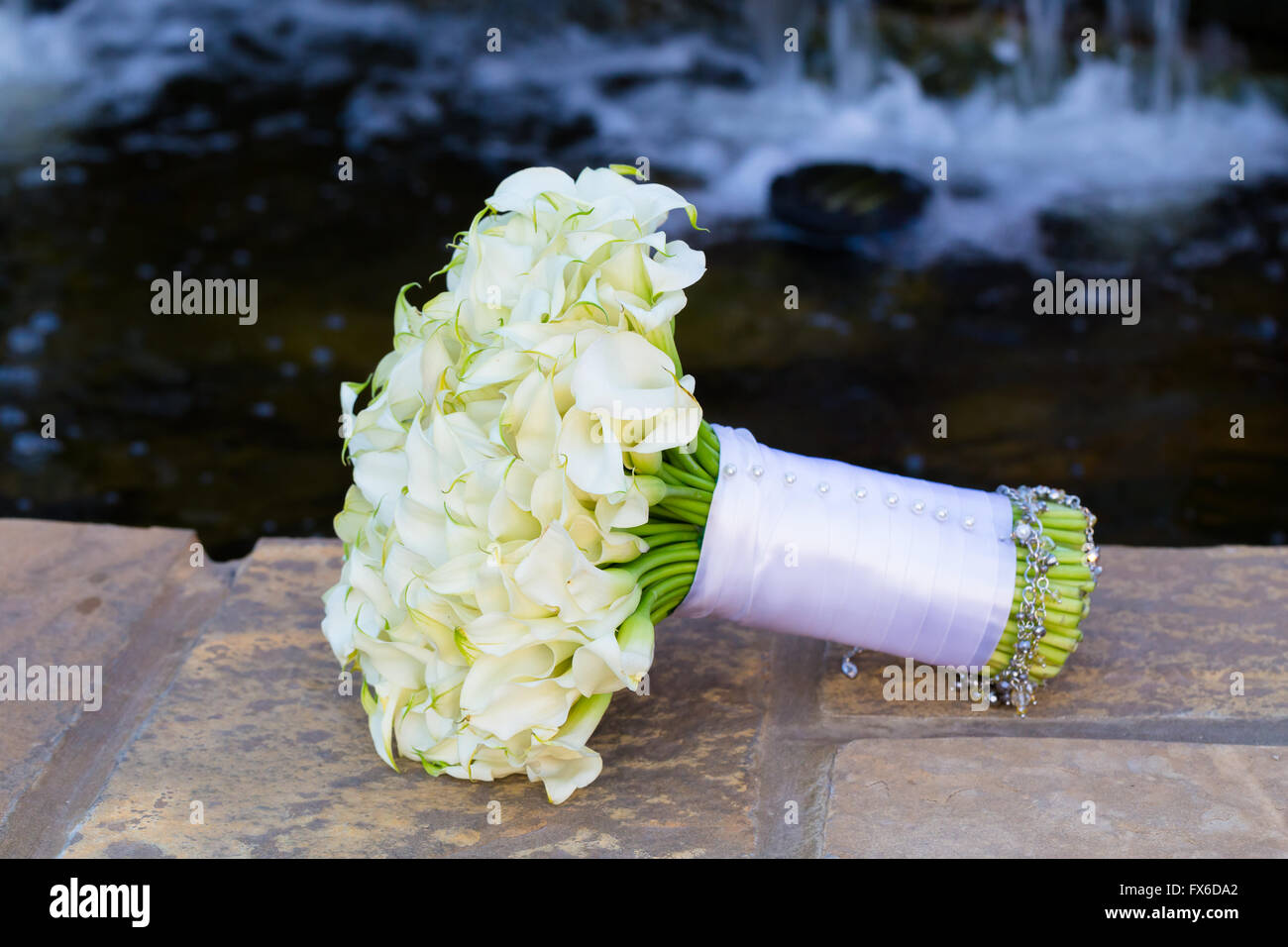 Fleurs Mariage organisé en un bouquet pour la mariée le jour de son mariage sur un mur de ciment avec de l'eau dans l'arrière-plan. Banque D'Images