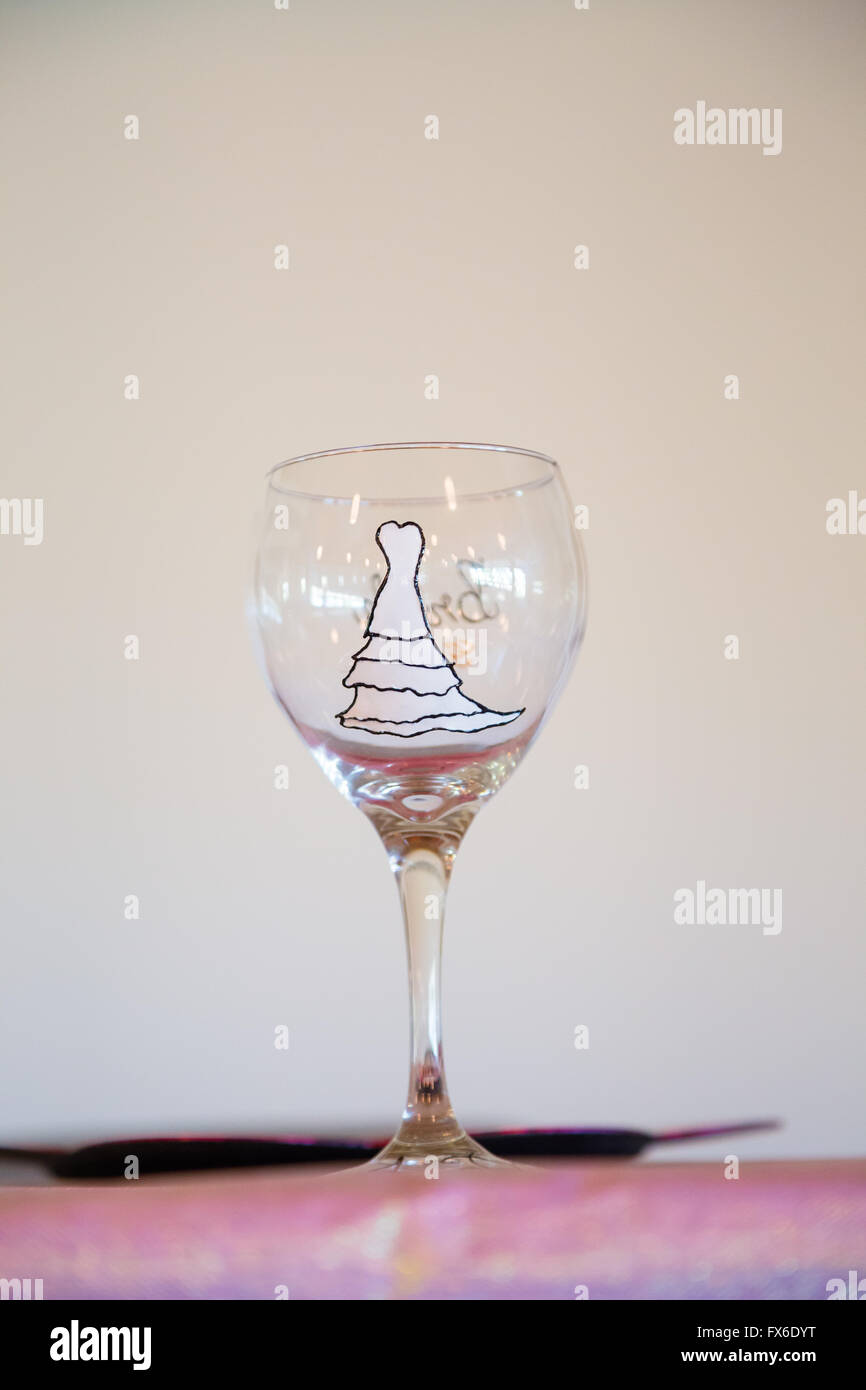 Verre à vin blanc peint avec une robe de mariage pour la mariée à sa réception. Banque D'Images