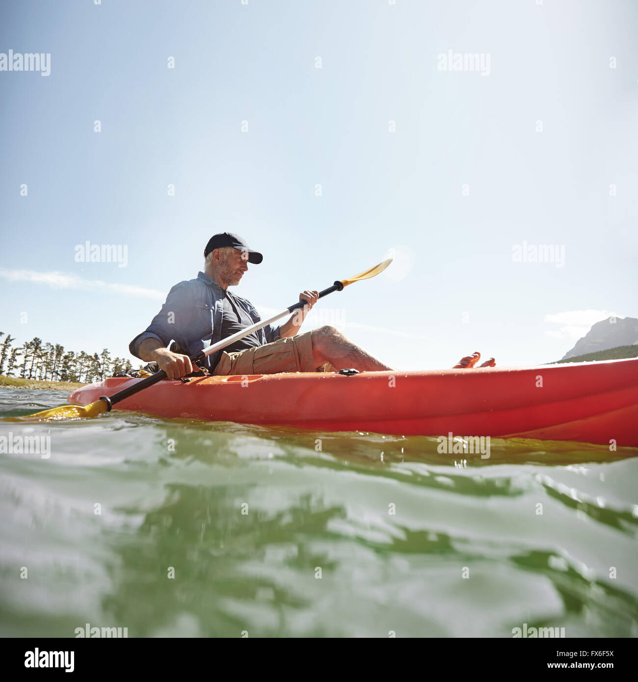 Shot of senior man kayak sur le lac un jour d'été. Une balade en kayak homme mûr dans le lac. Banque D'Images