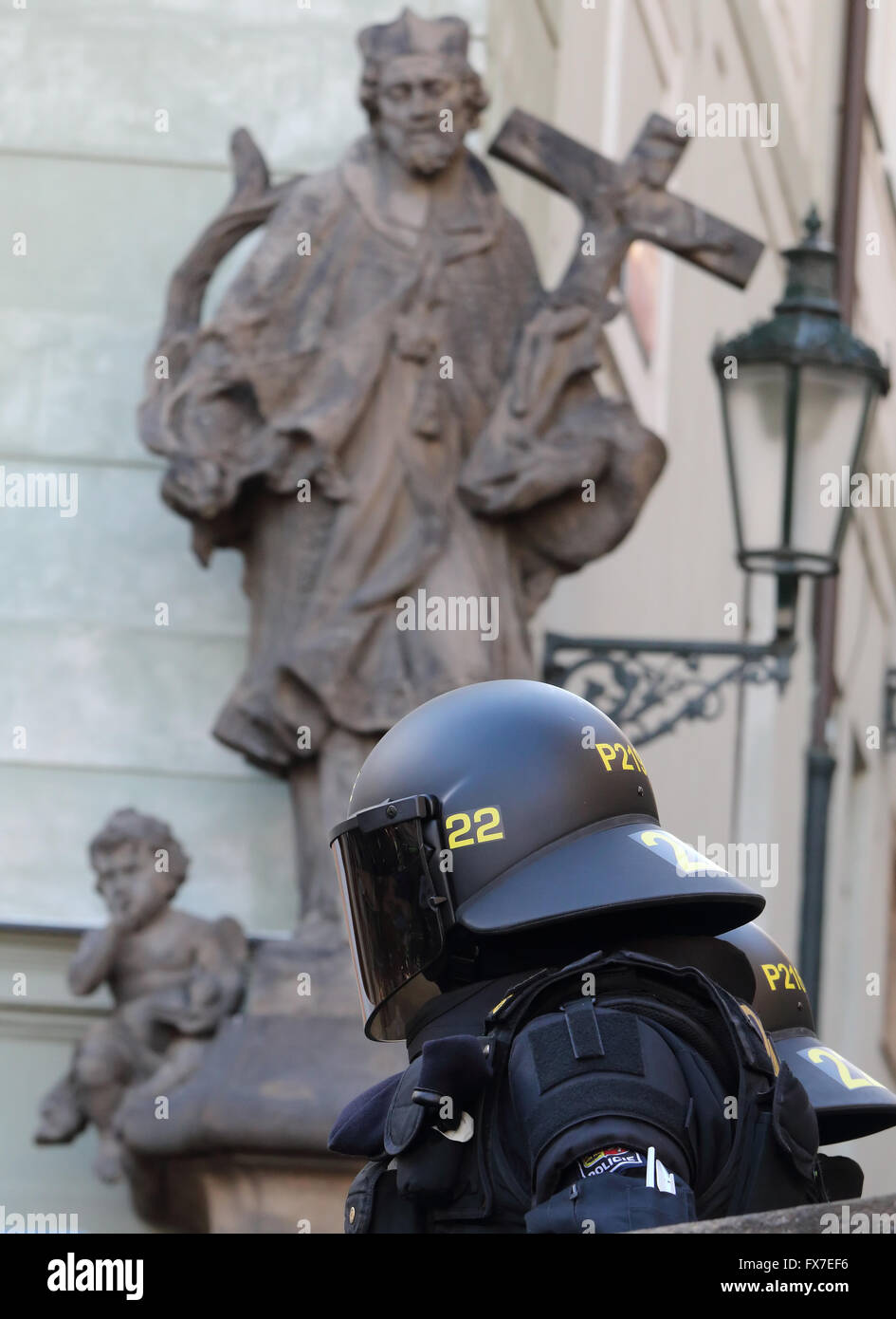 Agent de police antiémeute casquée sous une statue religieuse à Prague au cours de protestation contre le président Xi de la visite en Chine le 30/03/16 Banque D'Images
