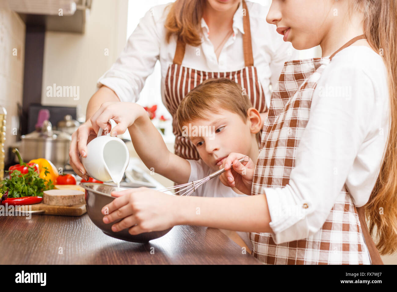 Mère avec des enfants la cuisson des œufs brouillés ou omelette dans la cuisine. Arrière-plan de cuisine familiale Banque D'Images