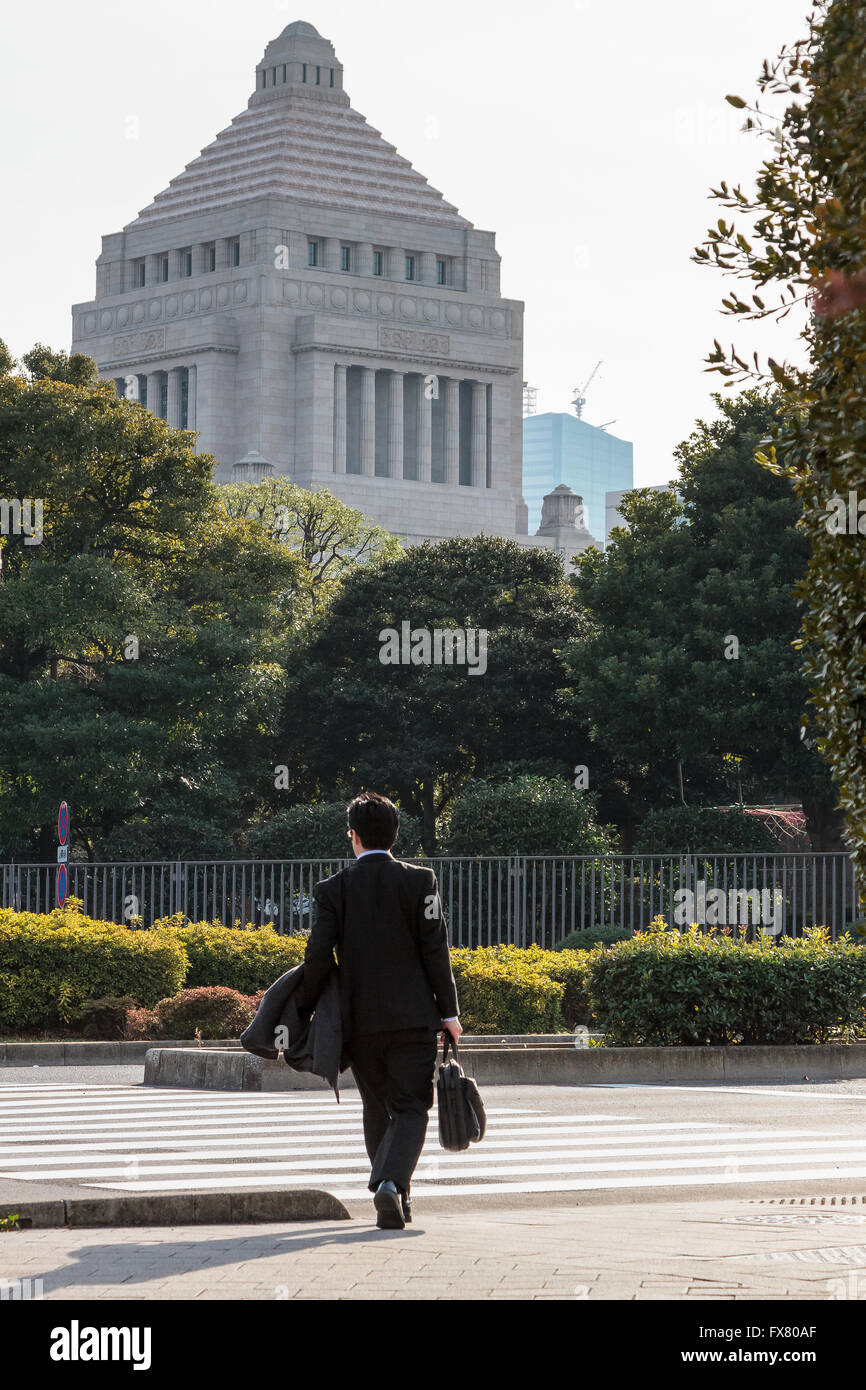 Un employé de bureau Japonais ou salaryman traverse une route près de la Diète japonaise (le Parlement), Nagatacho, Tokyo, Japon. Banque D'Images