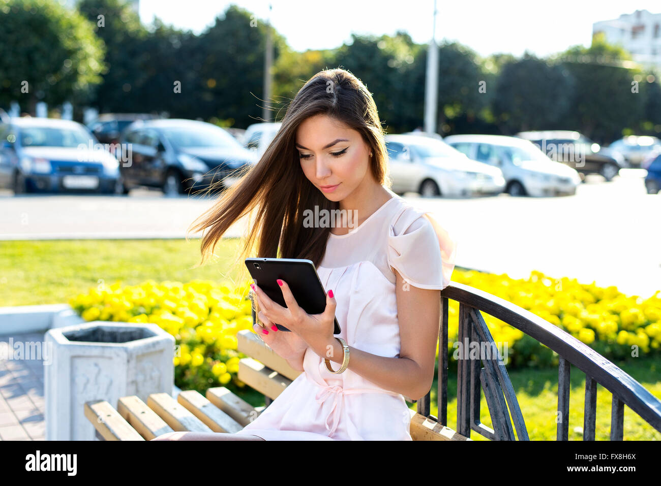 Beautiful Girl holding tablet, journée ensoleillée, sur un banc, le modèle de mode de vie urbaine. Lire des e-books, réseaux sociaux assis Banque D'Images