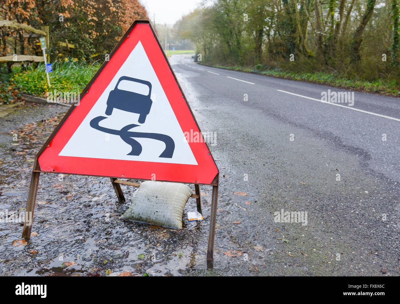 Route glissante de signalisation triangulaire sur une route inondée dans le Royaume-Uni. Banque D'Images