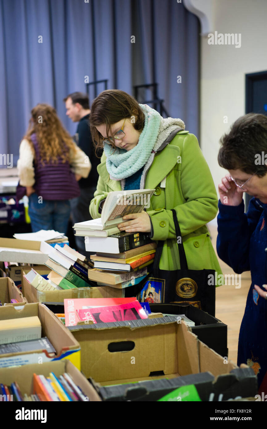 Une jeune femme attraper des brassées de second hand book affaires au l'Ystwyth Books shop vente de stocks excédentaires, le Pays de Galles UK Banque D'Images