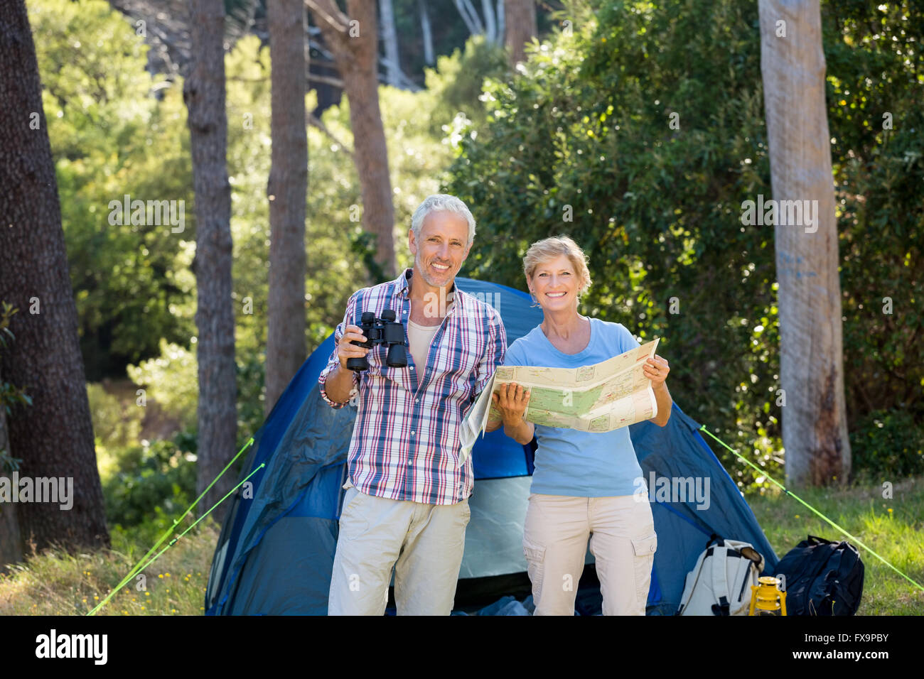 Young couple smiling and holding binoculars et carte Banque D'Images