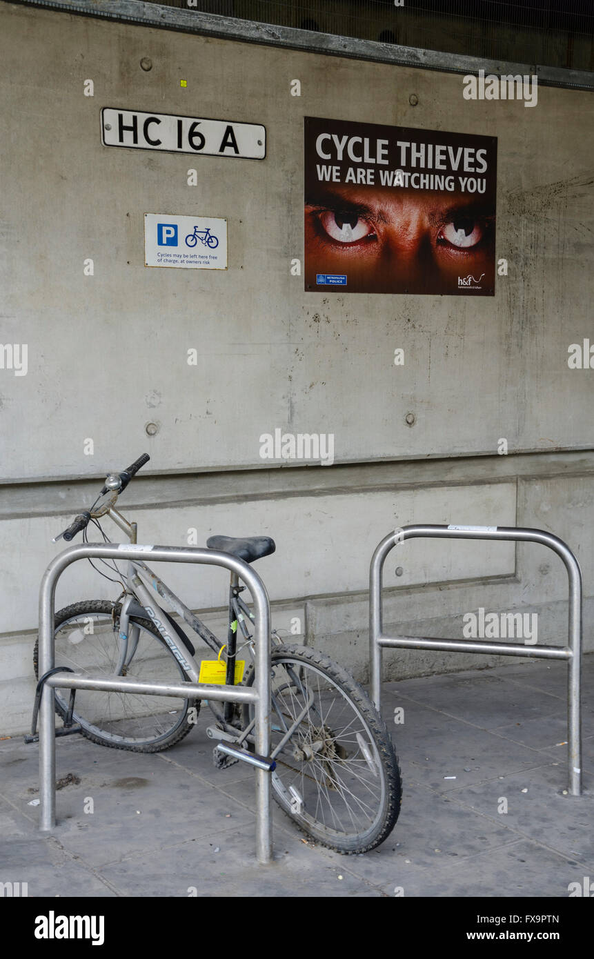 Un 'Cycle des voleurs nous vous observons' posté au-dessus d'un support à bicyclettes presque vide. Banque D'Images