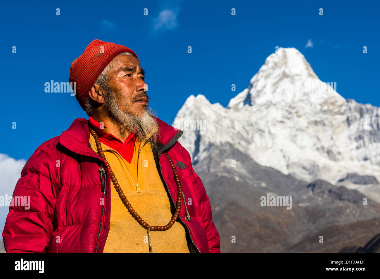 Portrait d'un moine bouddhiste à regarder vers le ciel, l'Ama Dablam (6856m) randonnée dans la distance, Pangboche, Solo Khumbu, Népal Banque D'Images