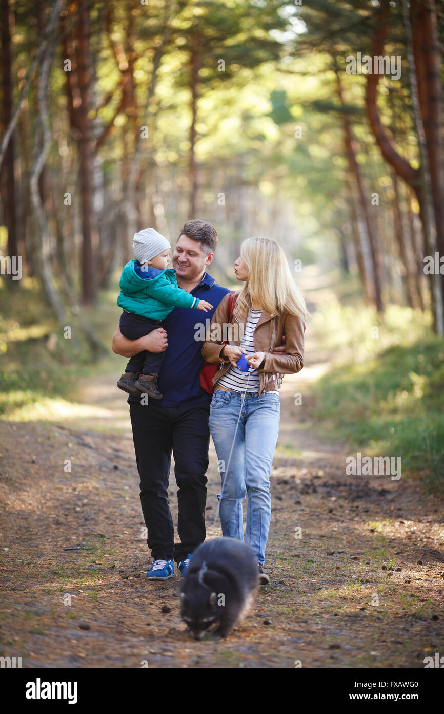 Famille heureuse avec le raton laveur la marche dans une forêt Banque D'Images