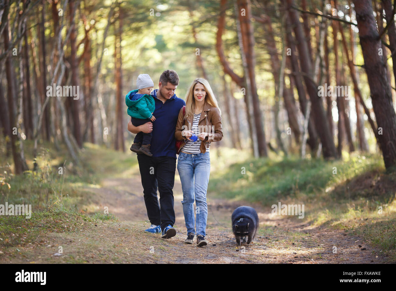 Famille heureuse avec le raton laveur la marche dans une forêt Banque D'Images