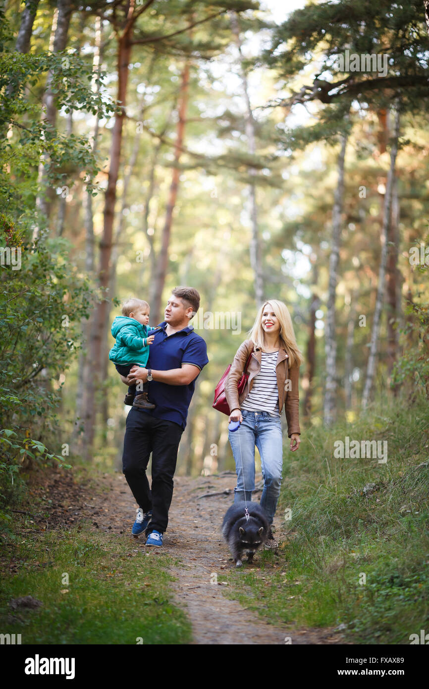Famille heureuse avec le raton laveur la marche dans une forêt Banque D'Images