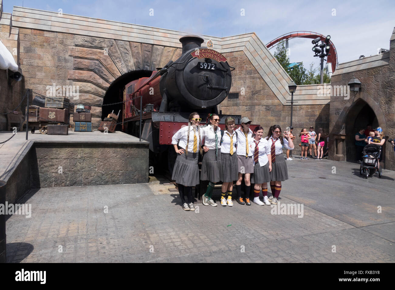 Les jeunes femmes vêtues de l'uniforme de la fille de l'école posent avec le Château de Poudlard Express Train Parc à thème Universal Studios Banque D'Images