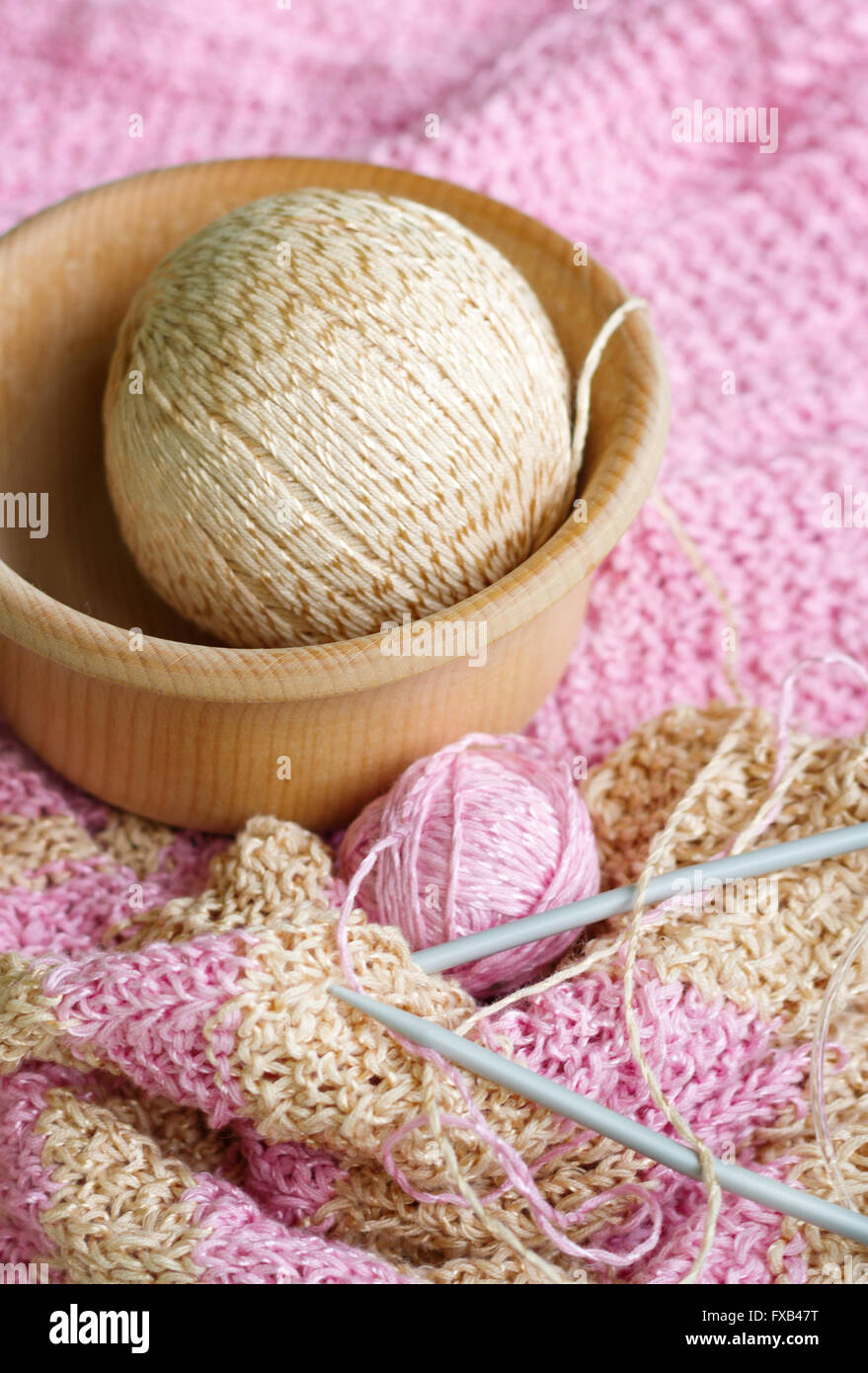 Belle écharpe en tricot à rayures, des aiguilles à tricoter et les deux billes de la laine sur un tableau blanc. Boules de laine couché dans un bol en bois. Yar Banque D'Images