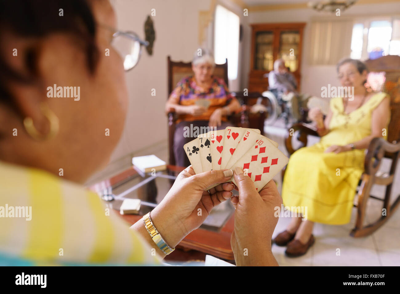 Les personnes âgées dans les soins gériatriques : groupe de femmes âgées de cartes à jouer et avoir du plaisir ensemble. Les personnes âgées mesdames s'asseoir sur le canapé de Banque D'Images