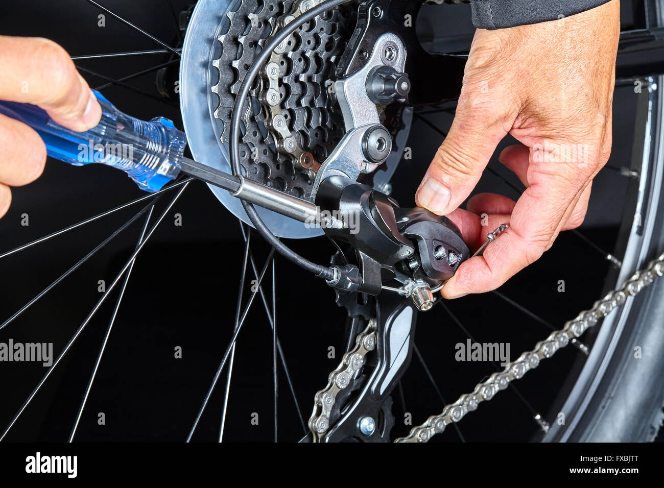 Man adjusting bicycle gear dérailleur avec des outils libre Banque D'Images