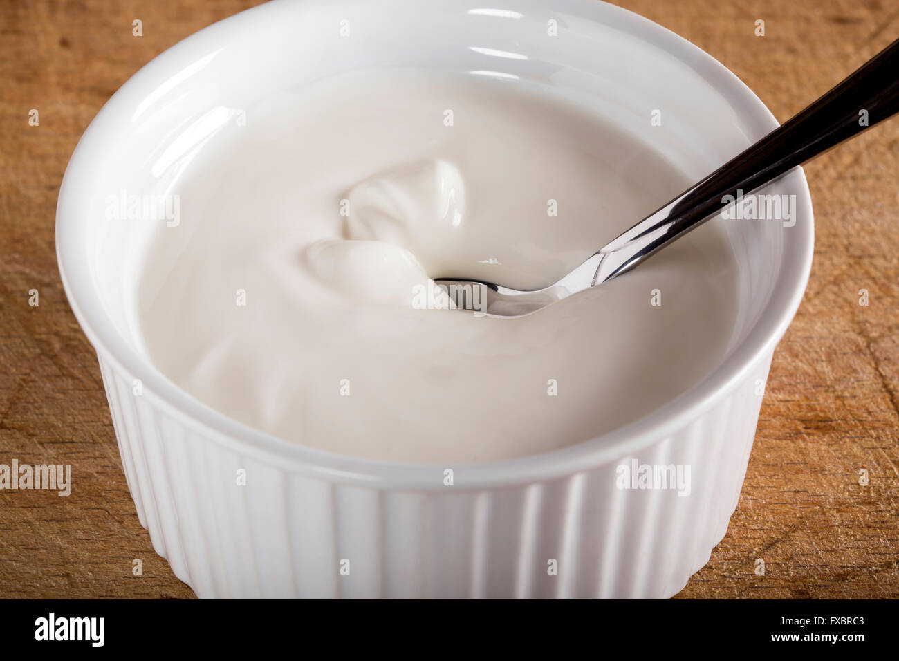 La crème sure dans un bol blanc avec cuillère Banque D'Images
