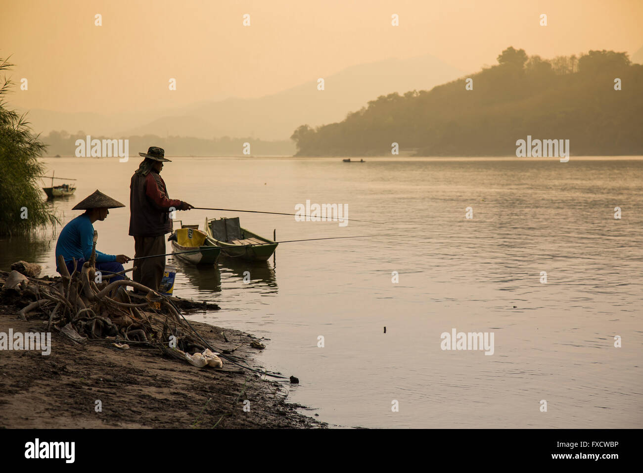 Luang Prabang, Laos - mars 2016. Deux hommes la pêche sur les rives du Mékong. Banque D'Images