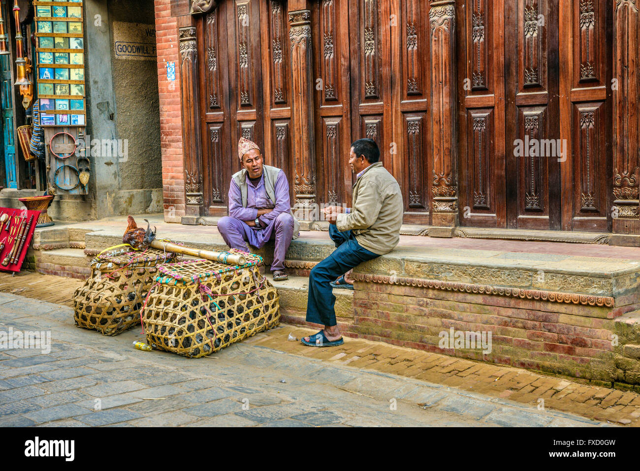 Deux hommes transportant des poules à vendre discuter dans la rue de Katmandou Banque D'Images