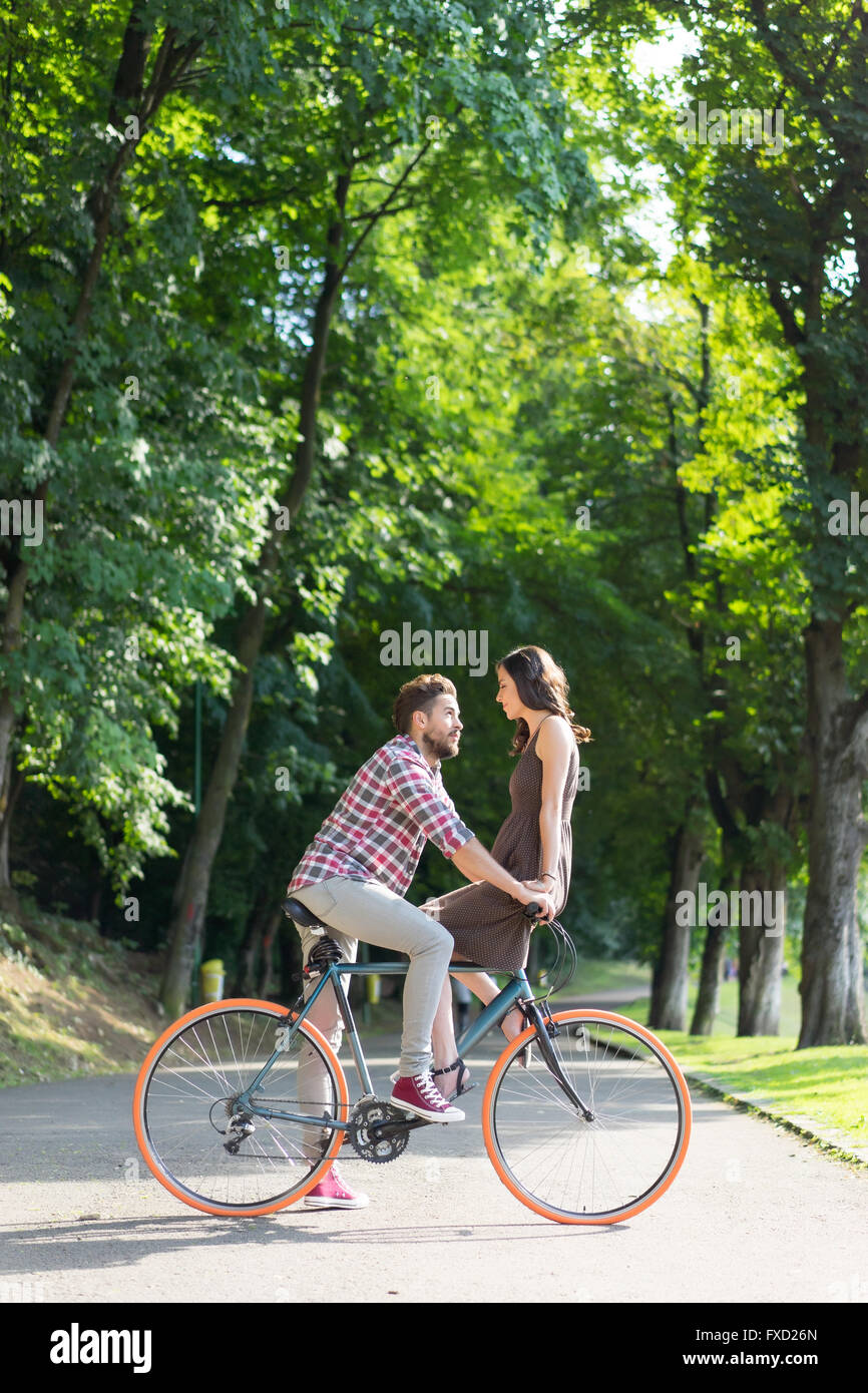 Avoir un amoureux des yeux, souriant et toucher les mains, debout sur un vélo sur une belle journée d'été Banque D'Images