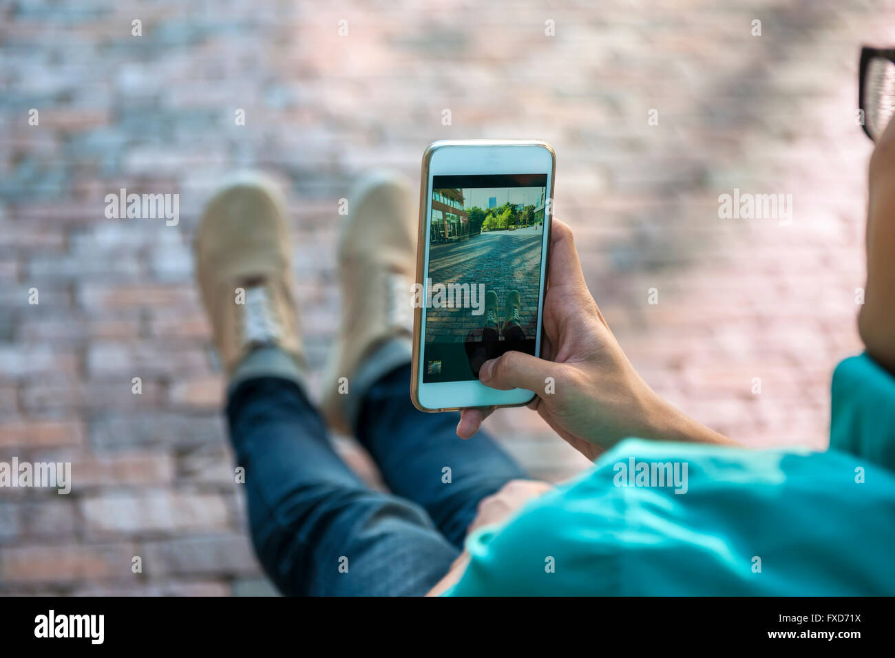 Young Asian man taking photo de rue et ses pieds avec smartphone Banque D'Images