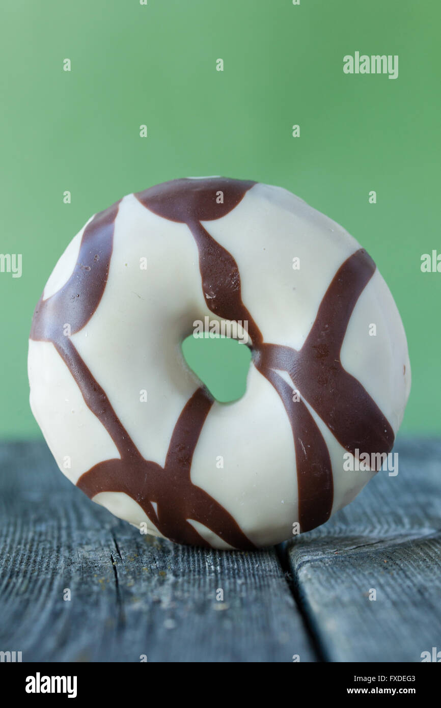 Délicieux donut avec frosting debout devant un arrière-plan vert Banque D'Images